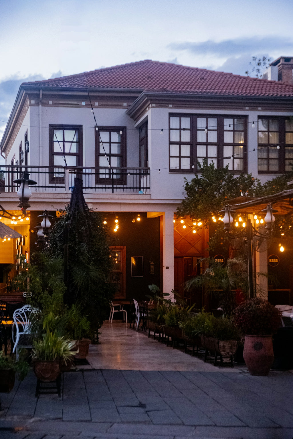 Hangulatkép / Symbolbild – fényfüzér étterem teraszán, régi épület előtt / Lichterkette auf Restaurantterrasse vor historischem Gebäude